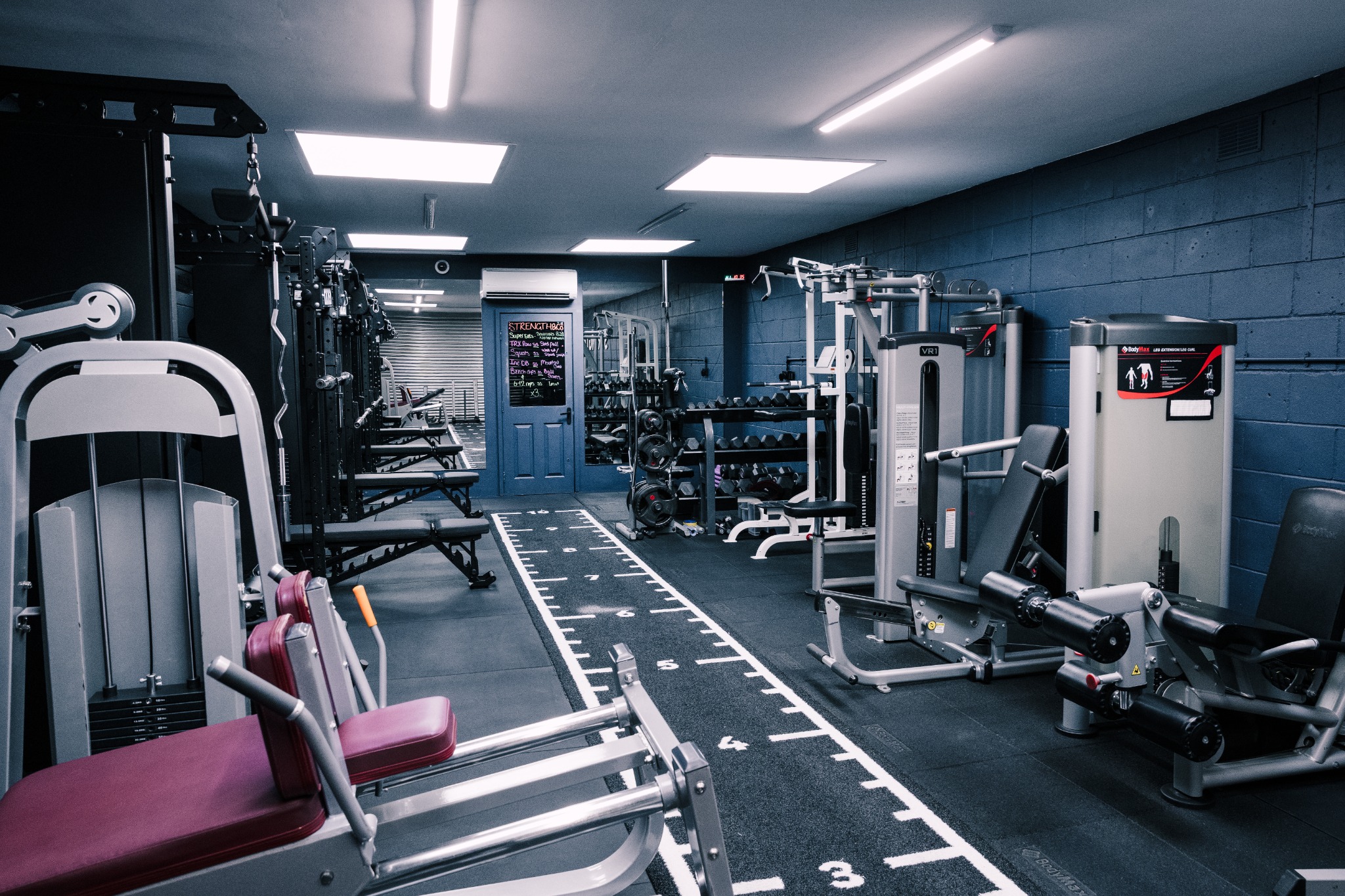 Inside the Strength & Co studio, with training equipment and a marked floor track